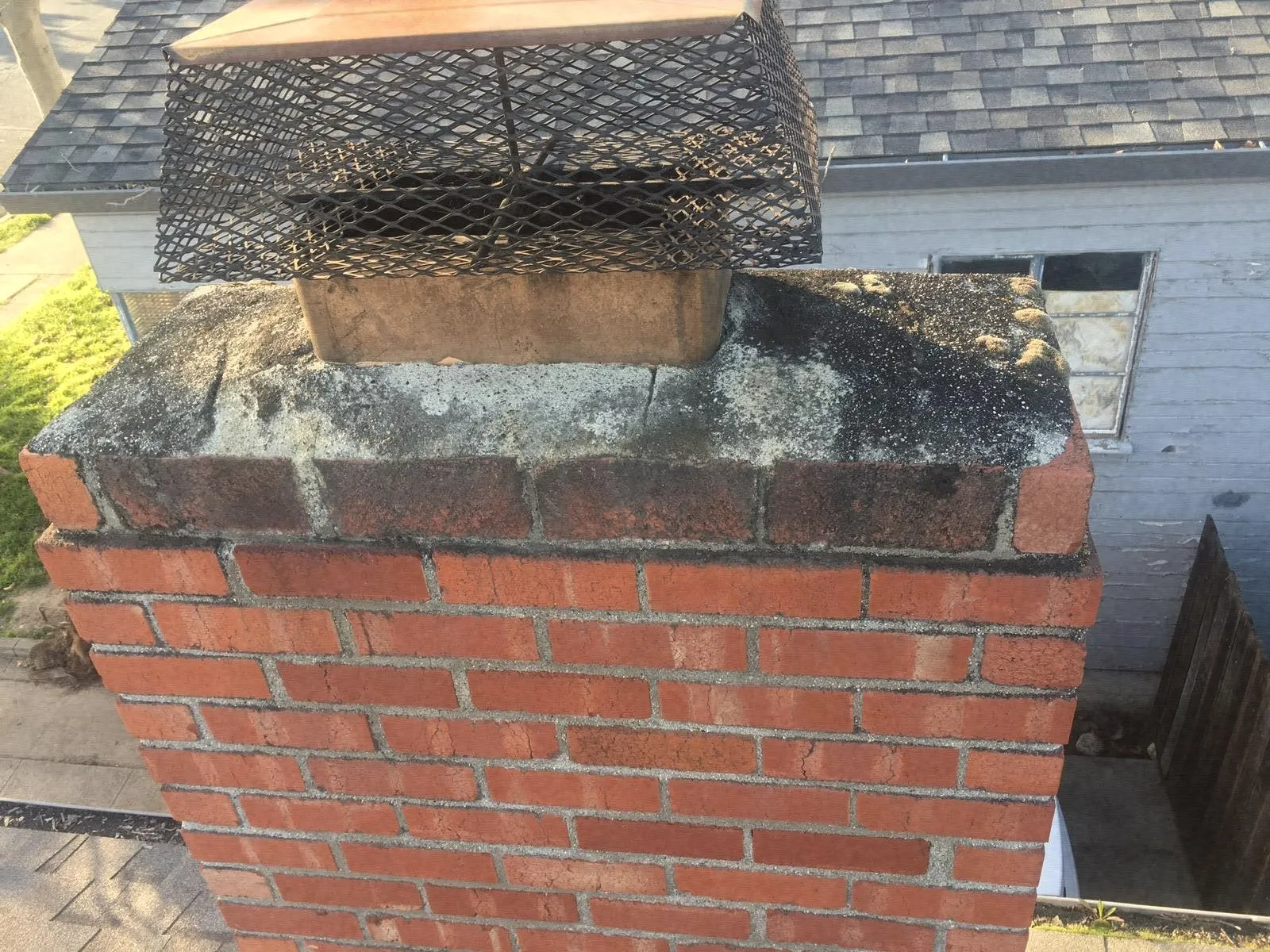 A black mesh chimney cap on a red brick stack