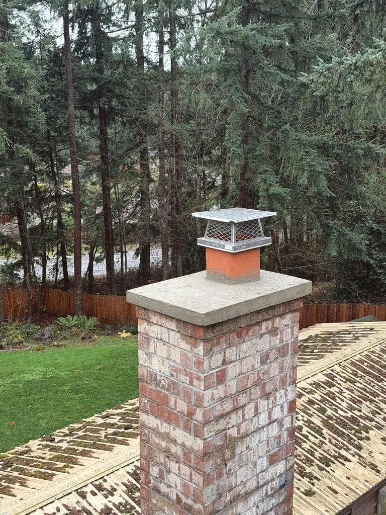 A concrete crown on a brick chimney, with a clay pot and a steel cap