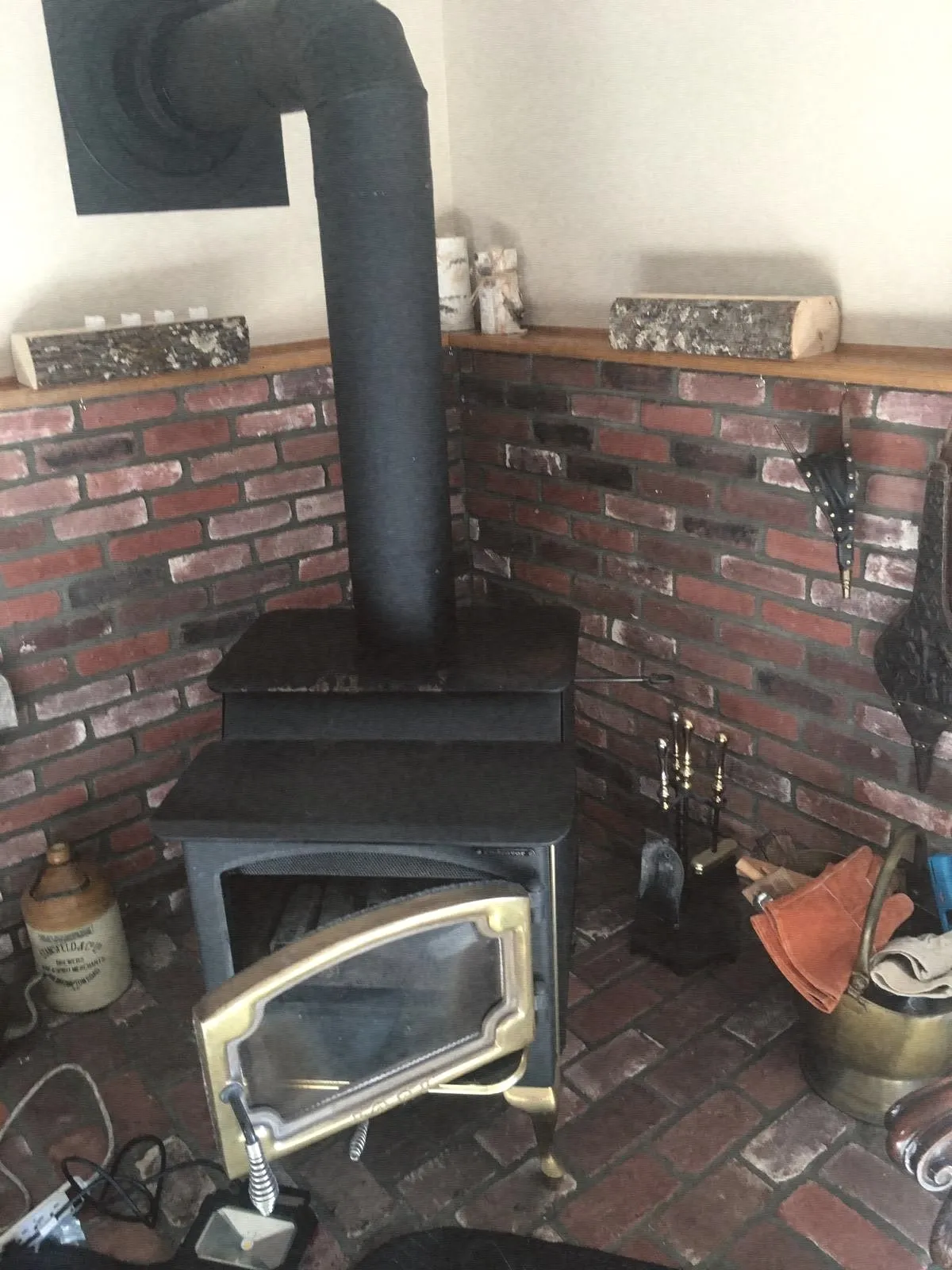 A black wood stove in a brick corner with its stove pipe